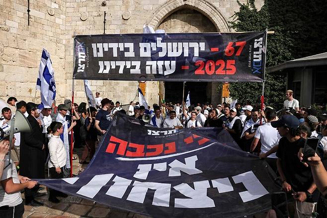 우익 활동가들이 26일(현지시각) 예루살렘 구시가지에서 “67년 예루살렘을 손에 쥐고, 2025년 가자를 손에 쥐고”라고 쓰여진 현수막을 들고 있다. 예루살렘/AFP 연합뉴스