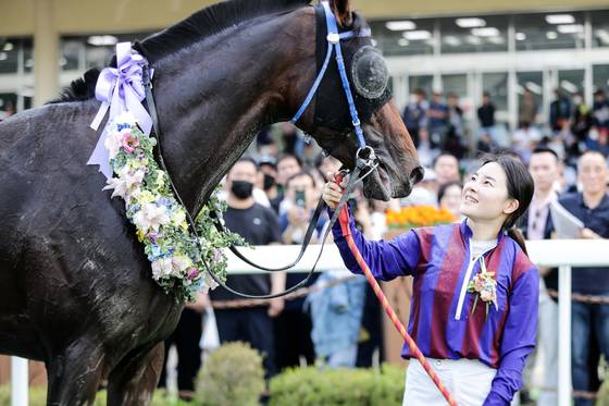 국내 최다 우승 및 최장수 여자 기수 기록을 보유한 김혜선 씨가 파트너인 경주마 글로벌히트를 보며 웃고 있다. 글로벌히트는 2023년 첫 승 이후 상금 45억원을 벌어들였다. [사진 마사회]