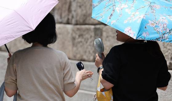 26일 서울 청계광장의 시민들이 양산과 손 선풍기로 더위를 식히고 있다. 기상청은 당분간 전국의 낮 최고기온이 25도 이상 오르는 초여름 날씨가 이어질 것으로 예보했다. [뉴스1]