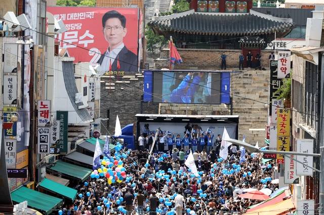 이재명 더불어민주당 대선 후보가 26일 경기 수원시 팔달문 영동시장 입구에서 집중유세를 하고 있는 가운데 김문수 국민의힘 대선후보의 대형 현수막이 눈에 띄고 있다. 뉴시스