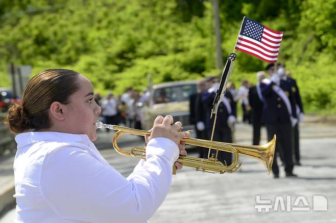 [힌스데일=AP/뉴시스] 26일(현지 시간) 미 뉴햄프셔주 힌스데일에서 열린 연례 메모리얼 데이(현충일) 퍼레이드 중 한 여학생이 트럼펫으로 추모곡 '탭스'(Taps)를 연주하고 있다. 2025.05.27.