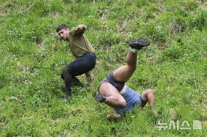 [브록워스=AP/뉴시스] 26일(현지 시간) 영국 글로스터셔주 브록워스의 쿠퍼스 힐에서 연례  치즈 굴리기 대회가 열려 남자부 참가자들이 언덕을 굴러 내려오고 있다. 이 대회는 약 180m 거리의 가파른 언덕에서 구르는 치즈를 잡아 결승선에 먼저 들어오는 사람이 우승하는 경기이다. 2025.05.27.