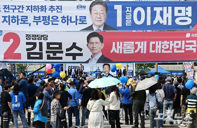 이재명 더불어민주당 대선 후보가 21일 인천 부평구 부평역 북광장에서 열린 집중 유세에 참석해 지지를 호소하고 있는 가운데 김문수 국민의힘 대선 후보의 현수막이 보이고 있다. 인천=류영주 기자