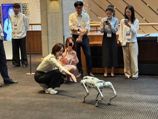 27일 서울 중구 신라호텔에서 열린 서울포럼 2025에서 참석자들이 유니트리의 70센티미터(CM) 사족보행 로봇의 재롱에 손을 내밀고 있다. /천민아 기자