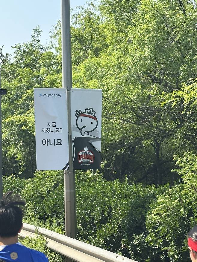 지난 25일 서울 여의도공원에서 열린 ‘무한도전 RUN with 쿠팡플레이’에서 ‘무한도전’ 명대사를 패러디한 응원문구 현수막이 내걸려 있다. 사진 하경헌 기자