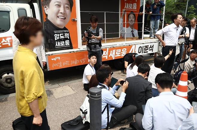 이준석 개혁신당 대통령 후보가 28일 서울 영등포구 여의도공원에서 유세를 마치고 취재진 질의에 답변하고 있는 가운데 한 시민이 이 후보가 전날 토론회에서 여성 신체를 묘사하며 젓가락 발언을 한 것에 대해 항의하고 있다.뉴스1