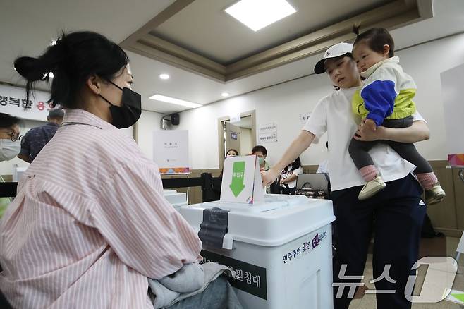 제21대 대통령선거 사전투표 첫날인 29일 부산 남구 용호4동주민센터 마련된 사전투표소에서 유권자가 아이를 안고 투표하고 있다. 2025.5.29/뉴스1 ⓒ News1 윤일지 기자