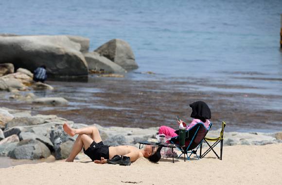 강원 강릉시 한 해변 백사장에서 관광객이 웃옷을 벗고 일광욕을 즐기고 있다. 2025.5.19 [사진=연합뉴스]