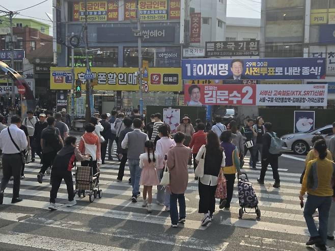 부산 시민들이 이재명·김문수 대선 후보 플래카드 앞 횡단보도를 건너는 모습./사진=유재희 기자.
