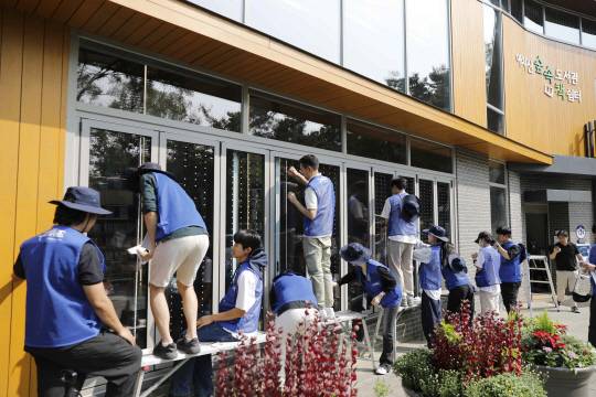 지난해 KCC 글라스 임직원과 관계자들이 아차산숲속도서관에 조류충돌방지스티커를 부착하고 있는 모습.   [KCC글라스 제공]