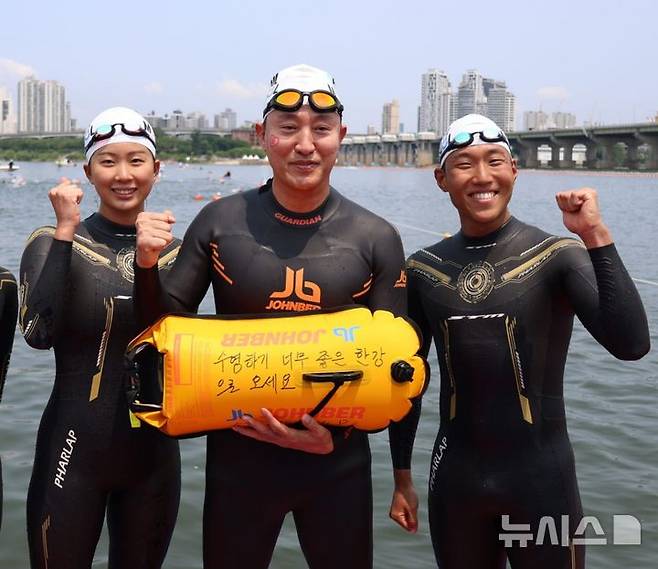[서울=뉴시스] 조수정 기자 = 오세훈(가운데) 서울시장이 30일 서울 한강에서 제2회 쉬엄쉬엄 한강3종 축제 사전점검 및 깨끗한 한강 수질을 홍보하기 위해 잠실대교 남단 수중보에서 뚝섬수상안전교육장까지 1km 구간을 시 소속 수영선수들과 함께 도하한 뒤 '수영하기 너무 좋은 한강으로 오세요'라고 적힌 부표를 들어보이고 있다. (사진=서울시 제공) 2025.05.30. chocrystal@newsis.com
