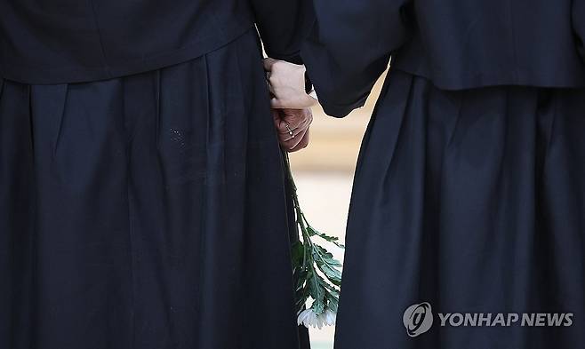 순직 해군 손에 들린 조화 (포항=연합뉴스) 윤관식 기자 = 30일 경북 포항시 남구 해군 항공사령부 체육관에 마련된 '해군 P-3CK 917호기 순직자 합동분향소'에서 순직 해군 유족들이 손을 잡고 서 있다. 2025.5.30 psik@yna.co.kr