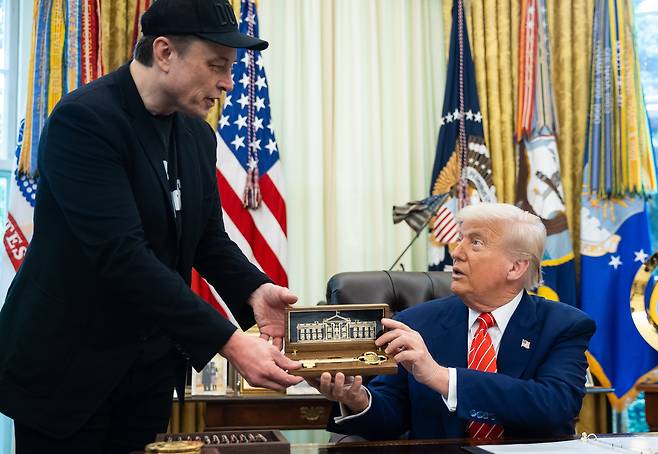 도널드 트럼프 미국 대통령이 30일(현지시각) 미국 워싱턴 D.C. 백악관 오벌 오피스에서 열린 기자회견 중 일론 머스크에게 '황금 열쇠'를 전달하고 있다./EPA연합뉴스