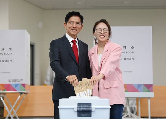 People Power Party candidate Kim Moon-soo, left, casts his ballot during early voting on May 29 at a community center in Gyeyang-dong in Incheon with his daughter Kim Dong-joo. [LIM HYUN-DONG]