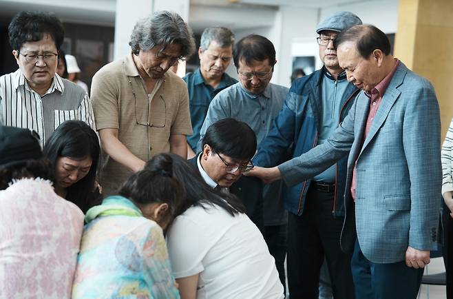 함께하는교회 성도들이 지난 15일 대전시 유성구 함께하는교회(김요한 목사) 지하 2층 갤러리에서 빛과소금교회의 최병진 목사와 김헌영 집사의 손을 잡고 기도하는 모습. 함께하는교회 제공
