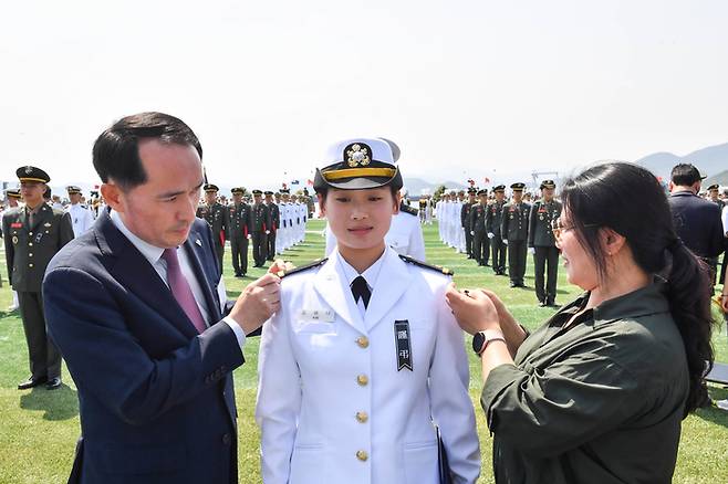30일 경남 창원시 진해구 해군사관학교에서 열린 제138기 해군·해병대 사관후보생 수료 및 임관식에서 천안함 46용사 고(故) 김태석 해군원사의 장녀인 김해나 소위가 어머니와 최원일 전 천안함장에게 계급장을 수여받고 있다. [사진 = 해군]