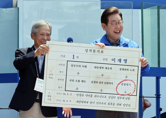 이재명 더불어민주당 대선 후보가 1일 오전 경북 안동시 웅부공원에서 유세 전 초등학교 은사인 박병기 씨로부터 성적표를 받고 있다. 김성룡 기자
