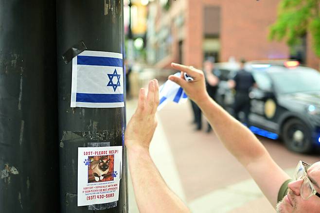 미국 콜로라도주 볼더에서 테러 공격으로 여러 사람이 다친 현장 근처에서 한 사람이 이스라엘 국기를 붙이고 있다. 로이터 연합뉴스