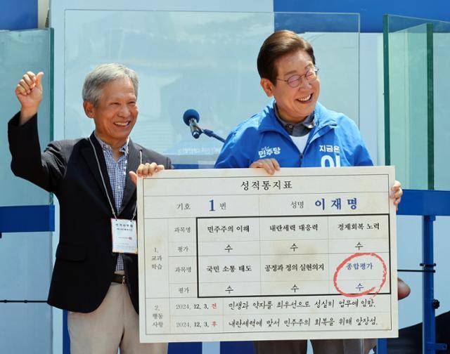 이재명 더불어민주당 대선 후보가 1일 경북 안동시 웅부공원에서 유세 전 초등학교 은사인 박병기씨로부터 성적표를 받고 있다. 안동=고영권 기자