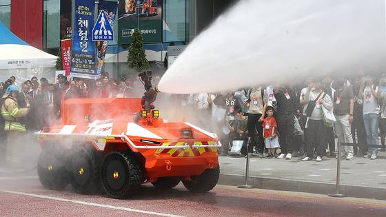 지난달 대구 북구 엑스코(EXCO)에서 개막한 '2025 국제소방안전박람회'를 찾은 관람객이 소방청과 현대자동차그룹이 공동 개발한 차량형 무인 소방로봇 시연을 지켜보고 있다. 국제소방안전박람회는 올해 21회쨰로 400여 개 기업이 역대 최대 규모인 1500여 부스 규모로 참가했다. [뉴스1]