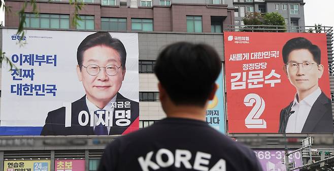 Large banners of Democratic Party candidate Lee Jae-myung (left) and People Power Party candidate Kim Moon-soo are displayed on a building in Uiwang City, Gyeonggi Province, on Monday, one day before the 21st presidential election. (Yonhap)