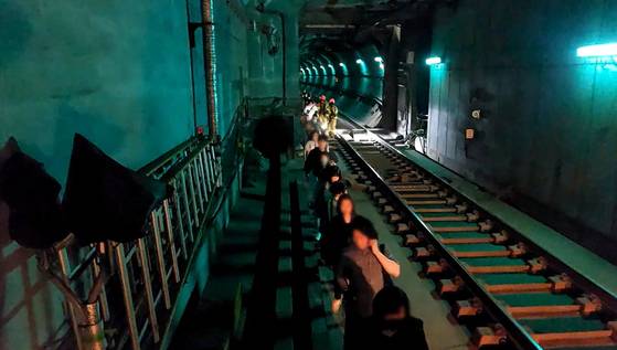 Passengers evacuate through an underground tunnel after a fire broke out on a Seoul Metro Line No. 5 train on May 31. [YEONGDEUNGPO FIRE STATION]