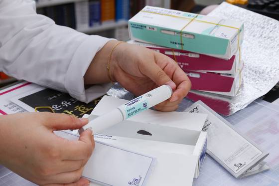 A pharmacist hands out a Wegovy pen at a pharmacy in Jongno District, central Seoul. [YONHAP]