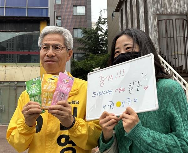 ▲“페미니스트 대통령 실존”이라고 쓴 화이트보드를 들고 온 한 여성은 권 후보에게 사탕 꾸러미를 건넸다. 사진=윤유경 기자.