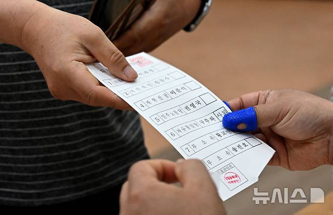 [광주=뉴시스] 김혜인 기자 = 제21대 대통령 선거일인 3일 오전 광주 광주 남구 양림동행정복지센터에 마련된 양림동 제1투표소에서 한 유권자가 투표용지를 건네받고 있다. 2025.06.03. hyein0342@newsis.com