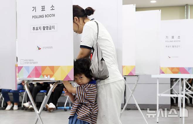 [부산=뉴시스] 하경민 기자 = 제21대 대통령 선거일인 3일 부산 연제구청에 마련된 연산제2동 제3투표소에서 한 어린이가 부모와 함께 기표소에 들어가 주위를 둘러보고 있다. 2025.06.03. yulnetphoto@newsis.com