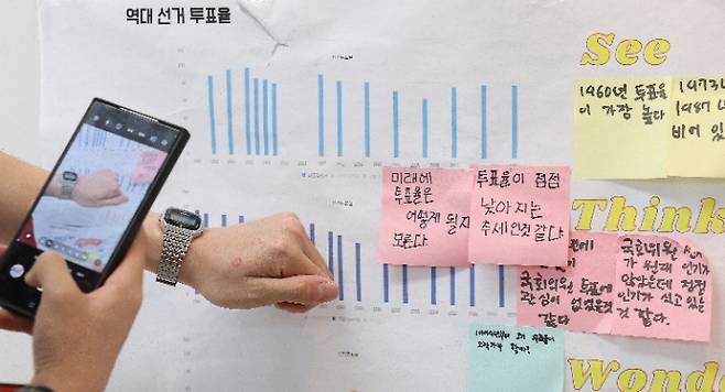 제21대 대통령 선거일인 3일 대구 중구 동덕초등학교 1층 드라마실에 마련된 삼덕동 제2투표소에서 투표를 마친 유권자들이 투표소 밖 게시판에 붙어있는 초등학생들의 투표율 분석 게시물 앞에서 '투표 인증샷'을 남기고 있다. 연합뉴스