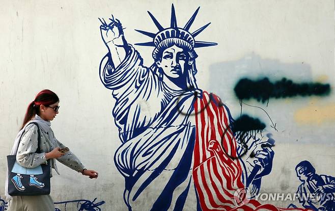 이란 테헤란 시내 지나가는 여성 (테헤란 EPA=연합뉴스) 지난 달 22일(현지시간) 이란 수도 테헤란 시내에 그려진 반미 벽화 앞을 지나가는 한 여성. 2025.06.03