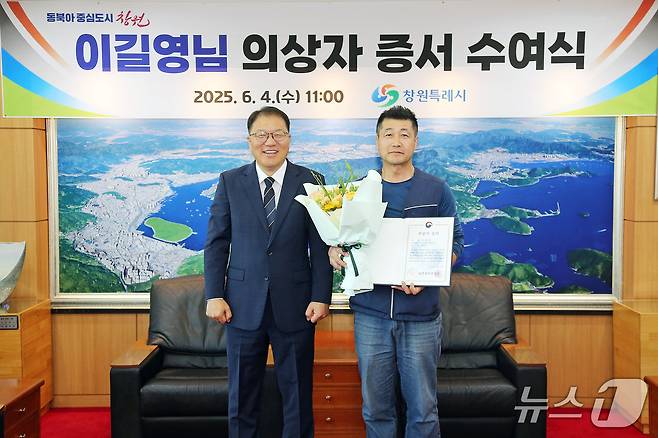 장금용 창원시장 권한대행(왼쪽)이 4일 시청에서 의상자로 선정된 이길영 씨에게 의상자 증서를 수여한 뒤 기념촬영을 하고 있다.(창원시 제공. 재판매 및 DB금지)