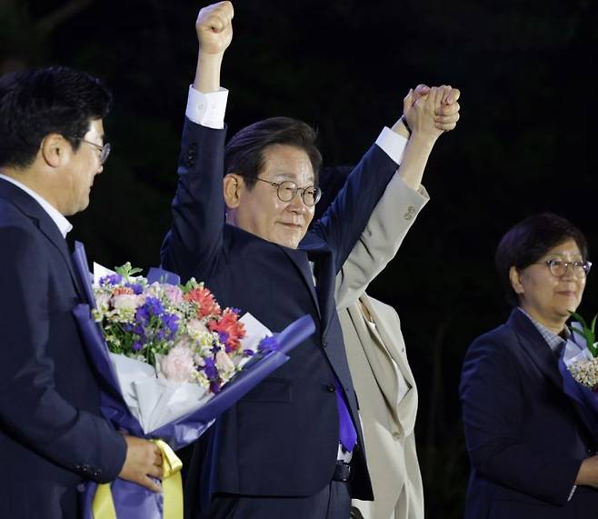 제21대 대통령 당선이 확실시되는 더불어민주당 이재명 대선 후보가 4일 서울 여의도 국회 인근에서 당 주최로 열린 국민개표방송 행사에 참석해 시민들을 향해 두 팔을 들어 인사하고 있다. 연합뉴스