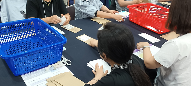 우편투표전담부의 개표사무원들이 회송용봉투에서 투표용지를 빼내고 있다. [지혜진 기자]