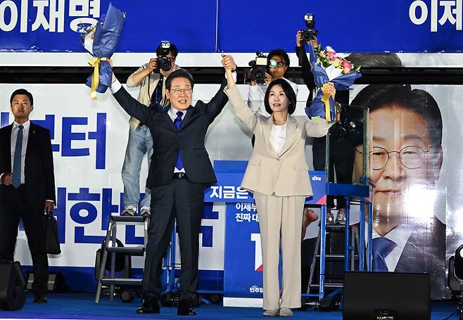 이재명 대통령이 4일 제21대 대통령 당선이 확실시 된 후 부인 김혜경 여사와 서울 여의도 국회 인근에서 당 주최로 열린 국민개표방송 행사에 참석해 시민들을 향해 두 팔을 들어 인사하고 있다. [공동취재, 연합]