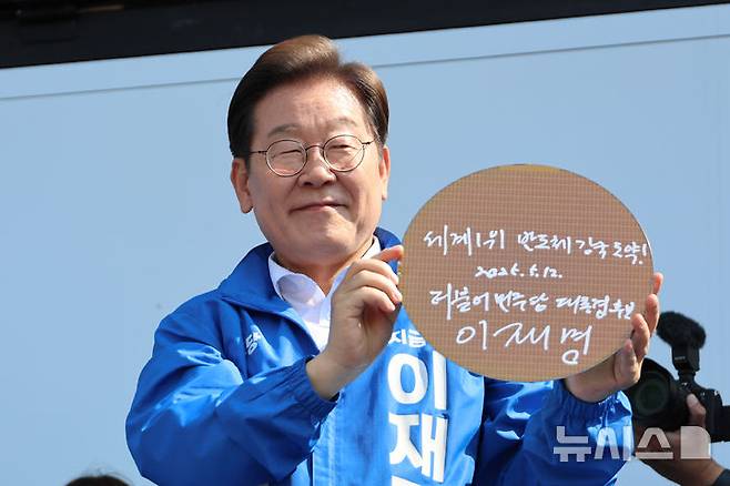 [화성=뉴시스] 조성우 기자 =이재명 더불어민주당 대선후보가 제21대 대통령선거 공식 선거운동이 시작된 12일 경기 화성시 동탄 센트럴파크 음악분수중앙광장에서 열린 집중유세에서 '세계1위 반도체 강국도약'이라고 쓴 반도체 웨이퍼를 들어보이고 있다. (공동취재) 2025.05.12. photo@newsis.com