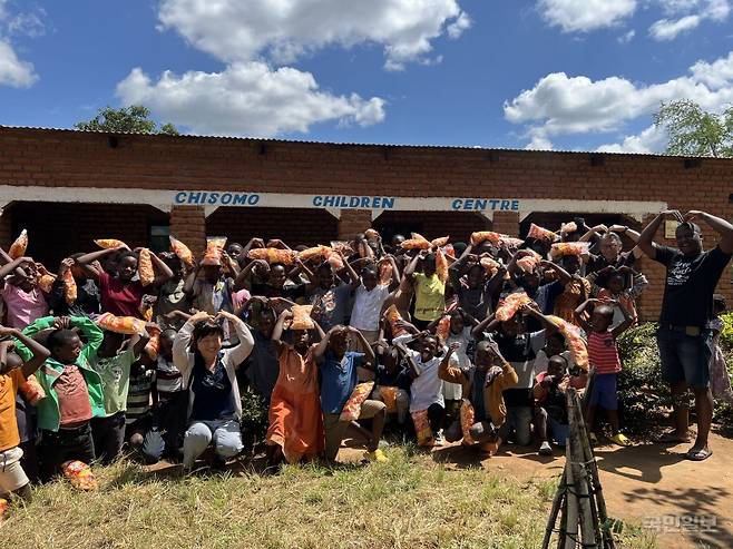 강지헌·주수경 말라위 선교사가 지난 4월 아프리카 말라위 구물리라 치소모아동센터 앞에서 센터 아이들과 함께 머리 위로 하트 모양을 하며 기념 사진을 찍고 있다.