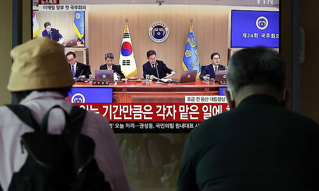 5일 서울 중구 서울역 대합실에서 시민들이 이재명 대통령 주재 국무회의 뉴스를 시청하고 있다. 뉴시스