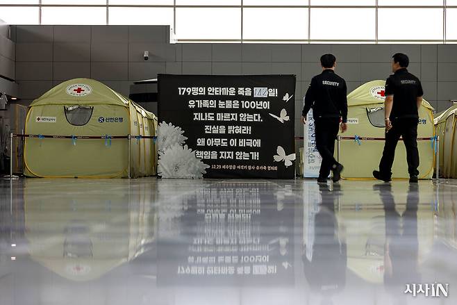 제주항공 참사 유가족들은 머물고 있는 무안공항 셸터 앞으로 공항 관계자들이 지나가고 있다 ⓒ시사IN 조남진