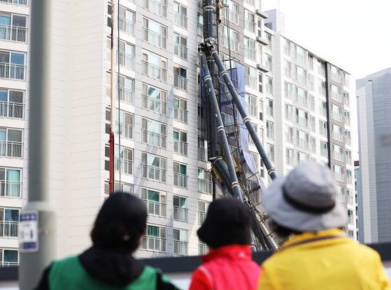 Onlookers on June 6 look at the construction drilling rig that fell on a residential building in Yongin, Gyeonggi, at 10:13 p.m. on June 5. [YONHAP]