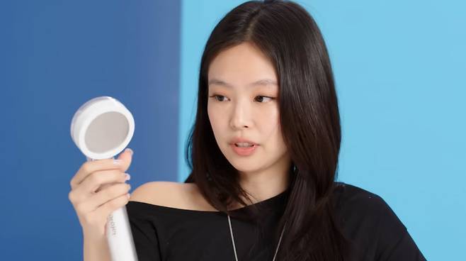 가수 제니가 여행 가방에 꼭 넣는다는 필터 샤워기 헤드를 들어 보이고 있다. /GQ 유튜브