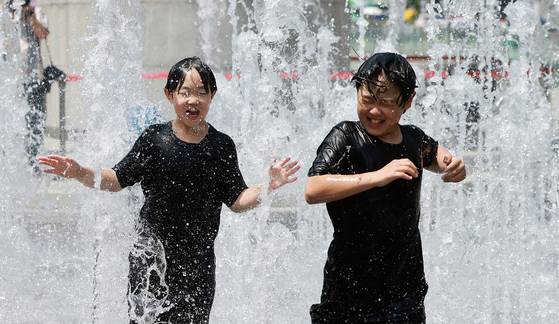 Children cool off at the fountain at Gwanghwamun Square in Jongno District, central Seoul, on June 6, amid early summer weather. [NEWS1]