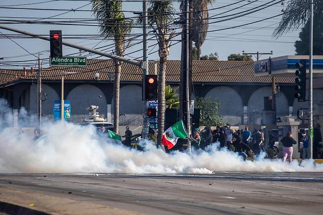 7일 캘리포니아주 로스앤젤레스에서 불법 이민자 체포에 반대하는 시위대와 이민 당국이 충돌한 가운데, 시위대가 최루탄을 피하는 모습./AFP 연합뉴스