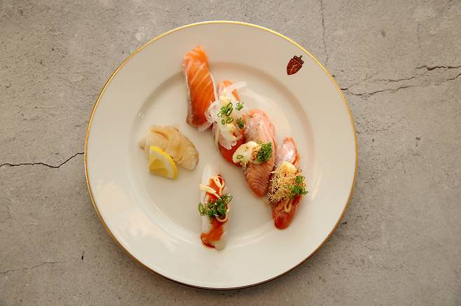 Norwegian salmon sushi topped with spicy buldak mayo and onion mayo sauces, along with a tasting of new farmed cod, is served by Japanese sushi chef Koji Nakamura during a luncheon hosted by the Norwegian Embassy in Seoul on Thursday. [NORWEGIAN SEAFOOD COUNCIL]]