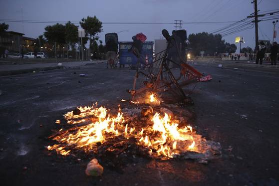 People shield themselves as a fire burns during a protest in Compton, Calif., Saturday, June 7, 2025, after federal immigration authorities conducted operations. [AP/YONHAP]