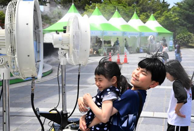 지난 7일 창원용지문화공원에서 열린 제17회 창원그린엑스포에서 아이들이 미스트 선풍기 앞에서 더위를 식히고 있다./성승건 기자/