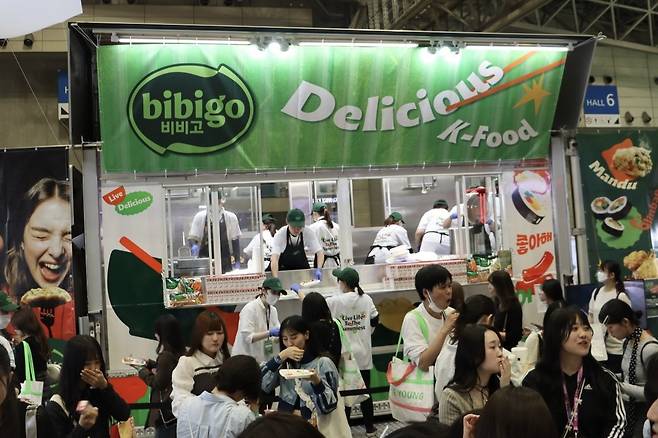 지난달 10일 일본 지바현 마쿠하리 멧세 ‘케이콘 저팬 2025(KCON JAPAN 2025)’ 현장에 마련된 비비고 부스에서 일본인 관광객들이 떡볶이·김밥·만두·미초로 구성된 한식을 시식하고 있다. CJ그룹 제공
