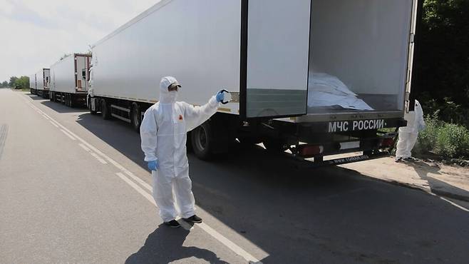 8일 러시아 국방부 관계자들이 우크라이나 국경과 인접한 벨라루스 남부 노바야 구타 인근에서 우크라이나 전사자들의 주검이 실려있다며 대형 냉장 트럭을 언론에 공개하고 있다. 러시아 국방부가 배포한 사진. AP 연합뉴스