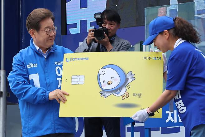 더불어민주당 이재명 대선 후보가 지난달 20일 경기 파주시 금릉역 중앙광장에서 열린 유세에서 지역화폐 모형을 전달받고 있다. [연합]